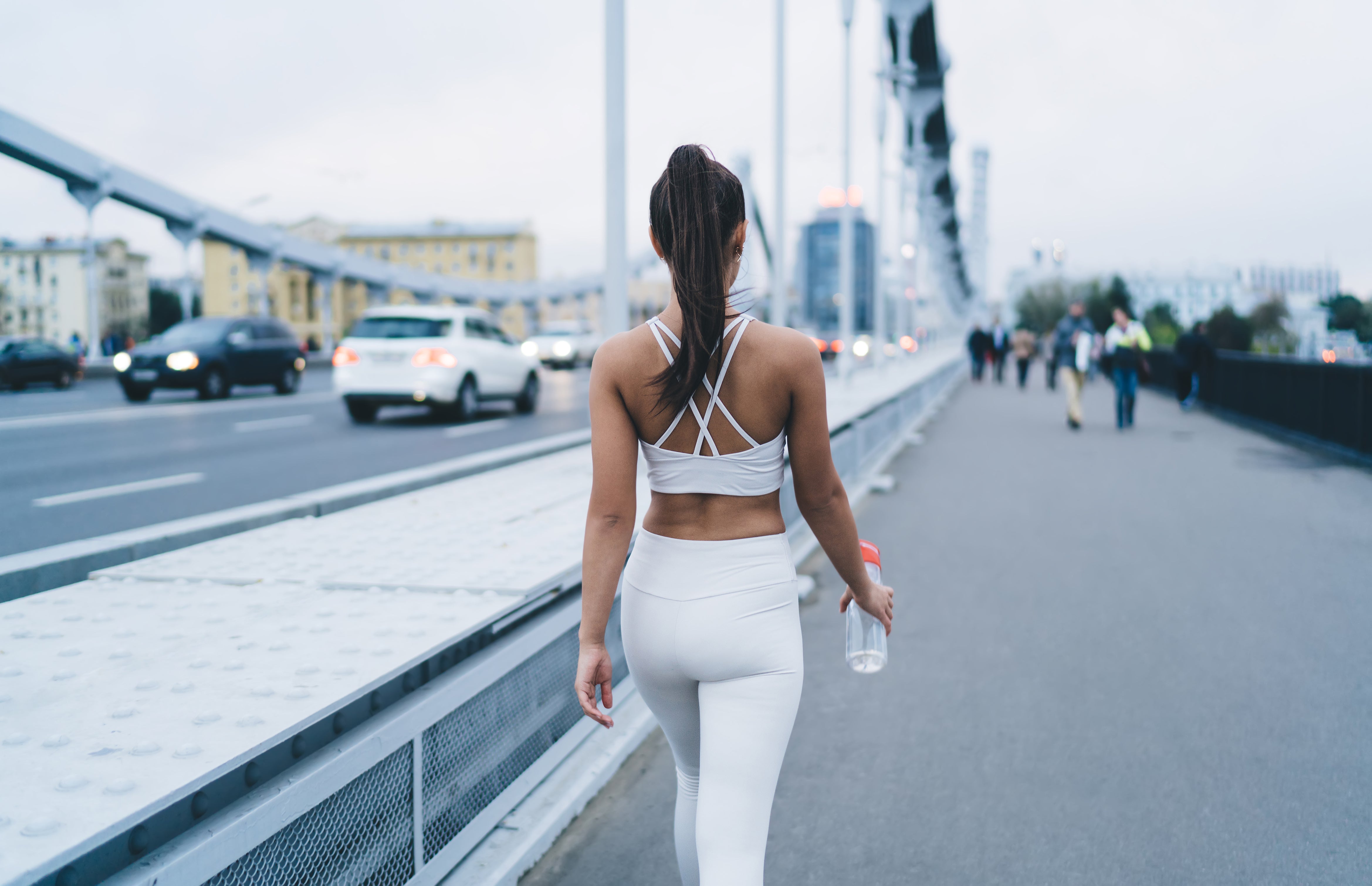athletic-woman-with-water-bottle-walking-on-bridge-2023-11-27-05-36-25-utc.jpg